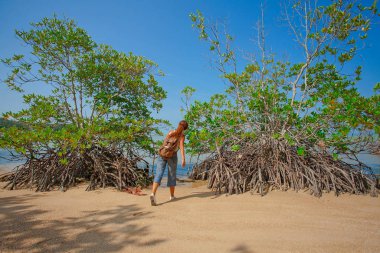 Kumsalda sırt çantalı genç bir kadın.