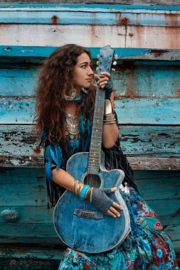 Teknede gitar çalan çekici genç hippi kadın.