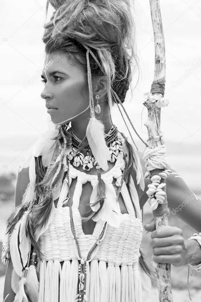 Attractive wild boho woman in native american style and white clothes posing at beach