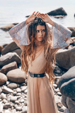 Güzel taş sahilde poz veren çekici boho kızı.
