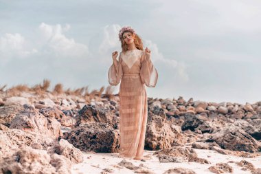 Güzel sahilde poz veren büyüleyici bir kadın.