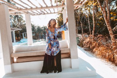 Otel odasında poz veren güzel, genç bir kadın. 