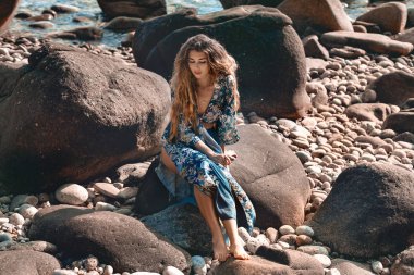 Güzel taş sahilde poz veren çekici boho kızı.