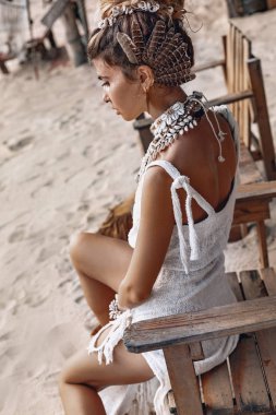 Gün batımında sahilde poz veren neşeli boho kadın.