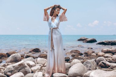Güzel taş sahilde poz veren çekici boho kızı.