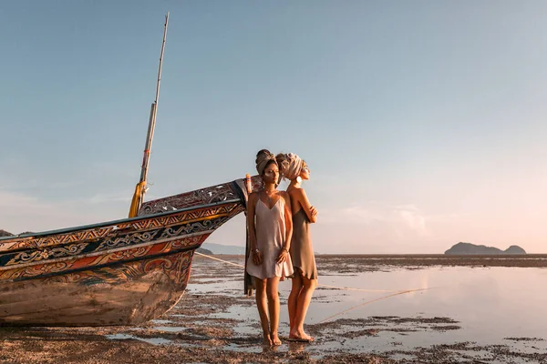 Duas meninas bonitas jovens em turbante na praia ao pôr do sol — Fotografia de Stock