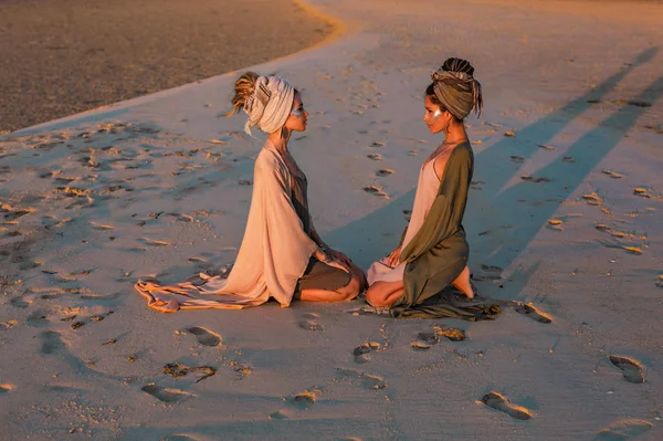 Dvě mladé dívky v turbanu na pláži při západu slunce — Stock fotografie