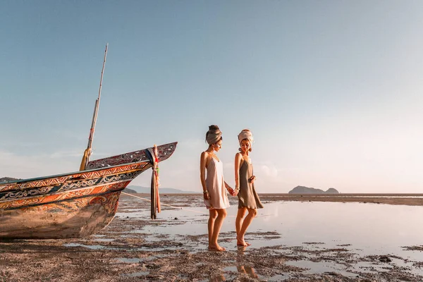 Dos chicas hermosas jóvenes en turbante en la playa al atardecer — Foto de Stock