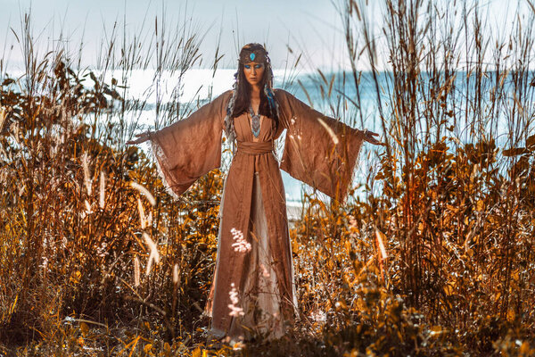 beautiful young woman in tribal costume outdoors at sunset