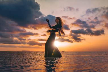 Gün batımında sahilde güzel genç bir kadın silueti.