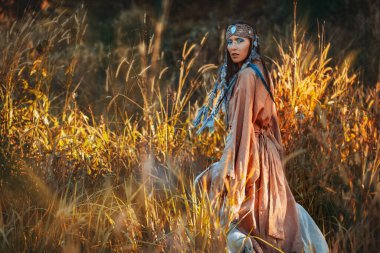 Gün batımında sahada genç ve güzel bir kadın. Doğulu kabile prensesi.