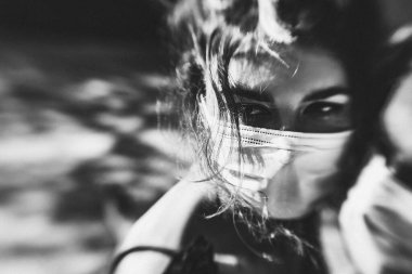 Genç çift kucaklaşırken yüz maskesi ve tıbbi eldiven takıyor.