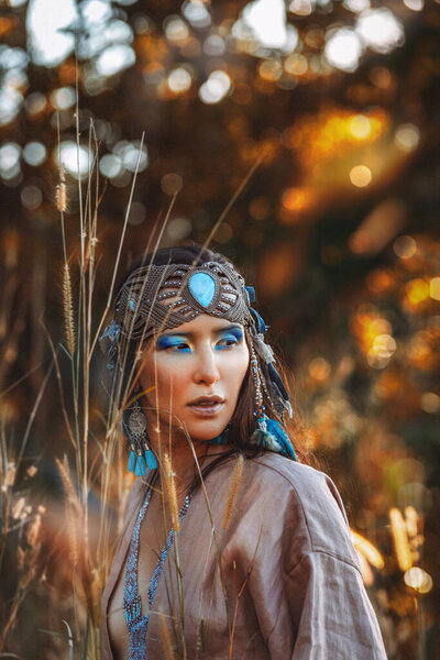 Beautiful young stylish woman on the field at sunset. Oriental tribal princess