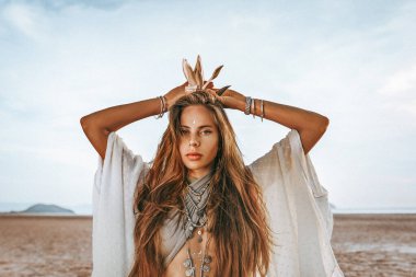 Gün batımında boho aksesuarlarıyla güzel, genç bir kadın.