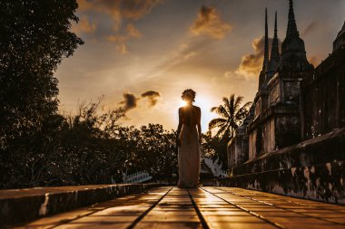 Gün batımında tapınakta yürüyen genç bir kadının silüeti.