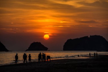 Sahilde birkaç siluet kişi kendi faaliyetleri var