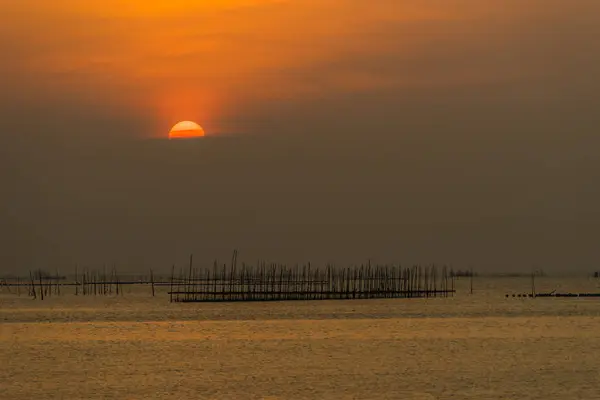 Sunset over the sea with fisherman's tool — Stock Photo, Image