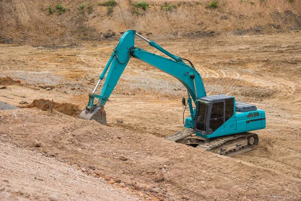 Blue backhoe excavating soil and sand