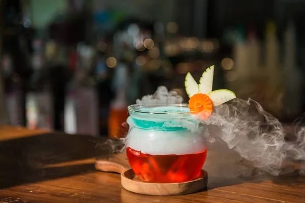 Коктейльный напиток в голубой форме с дымом на деревянной тарелке — стоковое фото