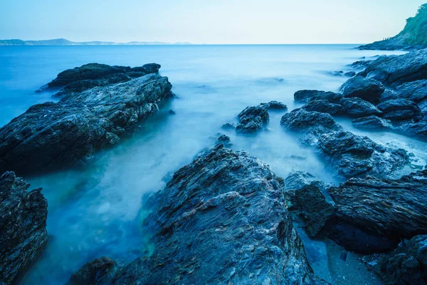 Mar sedoso con roca en la costa y cielo azul — Foto de Stock