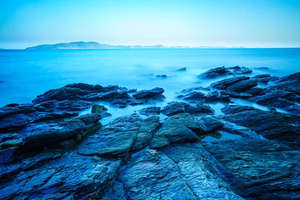 Mar sedoso con roca en la costa y cielo azul — Foto de Stock