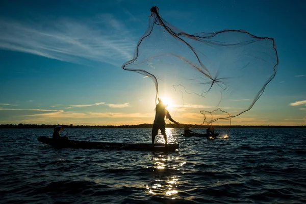 Niet-geïdentificeerde silhouet fisher man op boot vissen door het gooien van — Stockfoto