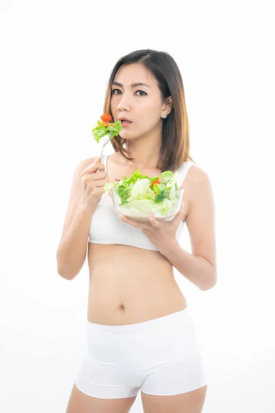 穿着白色运动胸罩的美丽的亚洲年轻女子健康食品吃着有着白色背景的健康食品沙拉 — 图库照片