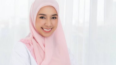 Pembe başörtülü gülümseyen Asyalı müslüman kadının portresi. Öpücük gönder. Mutlu an konsepti.