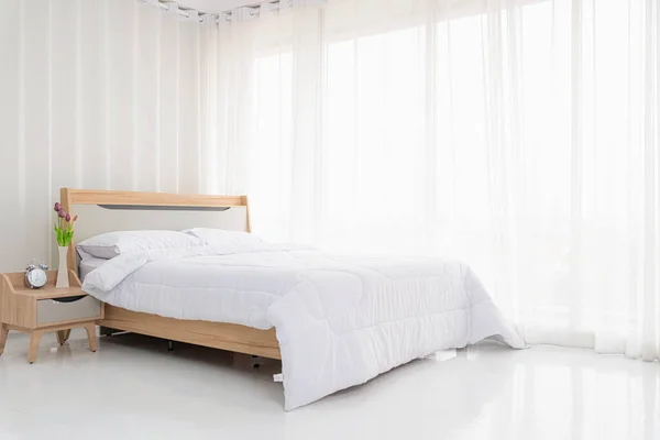 Interior white bedroom with white curtains and white pillows on wooden bed elegant classic for rest and sleep. Modern white bedroom bright.