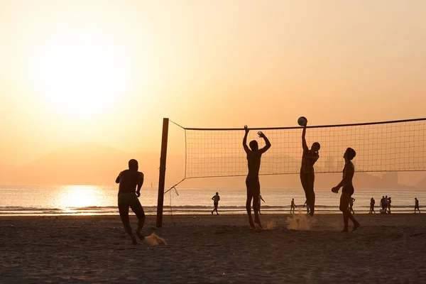 Sportowcy ćwiczą siatkówkę plażową podczas letniego zachodu słońca — Zdjęcie stockowe