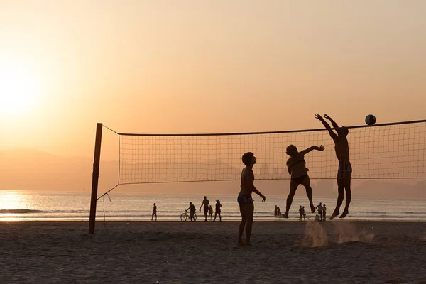 Atletas praticando vôlei de praia durante o pôr do sol de verão — Fotografia de Stock