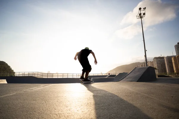 Menino praticando skate durante o pôr do sol — Fotografia de Stock