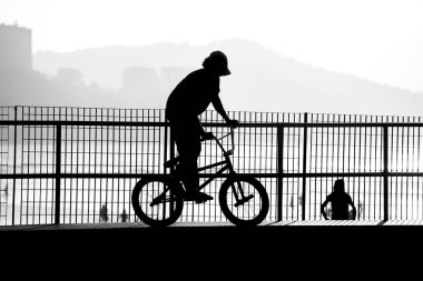 Bir BMX bisikletçisinin silueti kaseye düşmeye hazırlanıyor..