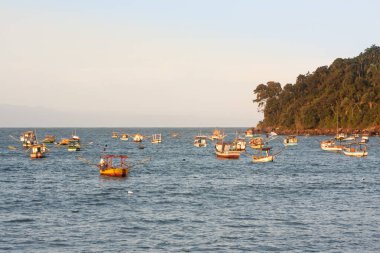 Perequ sahilinde gün batımında demirlemiş balıkçı tekneleri, Guaruja, Brezilya.