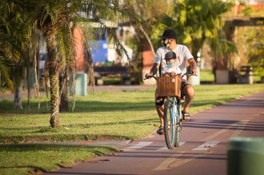 Santos, Brezilya. 09 Mayıs 2020. Babası bisikletle Santos, Brezilya 'da karantina sırasında oğlunu gezdiriyor..