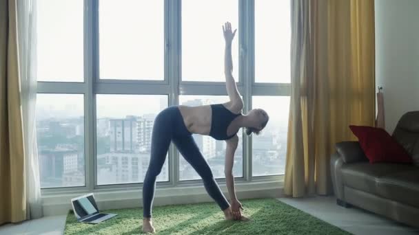 Mujer joven practicando yoga en casa con fondo de paisaje urbano — Vídeos de Stock