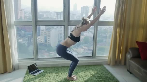 Ung kvinna utövar yoga hemma med stadsbilden bakgrund — Stockvideo