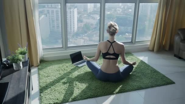 Chica joven practicando meditación en casa con fondo de paisaje urbano — Vídeos de Stock