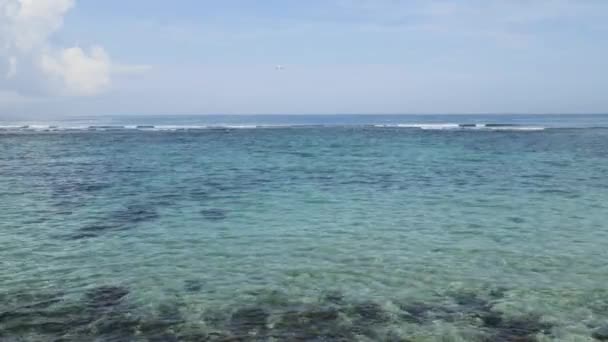 Avión aterrizando en la isla Aeropuerto de Bali bajo el mar azul con olas en el horizonte — Vídeos de Stock