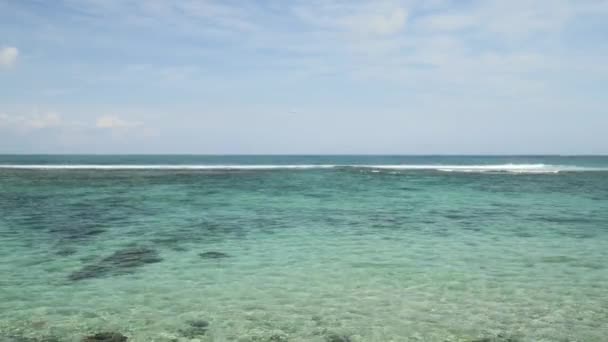 Vliegtuig landing op het eiland Bali luchthaven onder blauwe zee met de golven op de horizon — Stockvideo