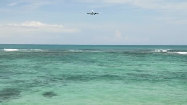 Avión aterrizando en la isla Aeropuerto de Bali bajo el mar azul con olas en el horizonte — Vídeos de Stock