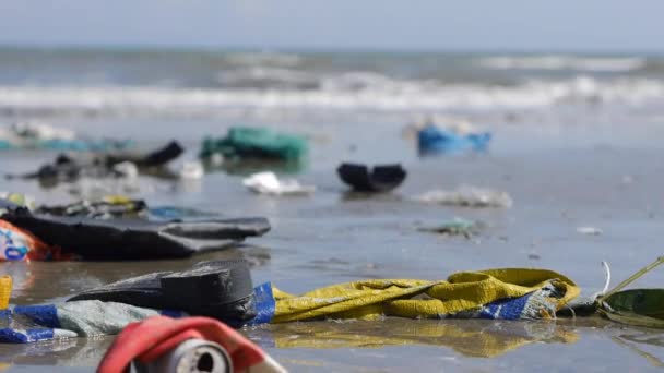 Handheld close up pan shot of trash and rubbish on seashore on sea background — Stock Video