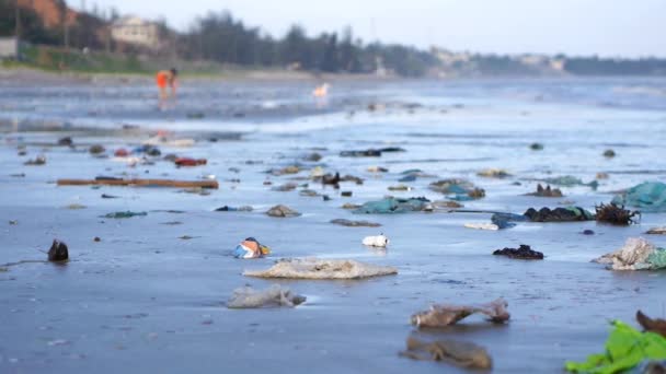 Παιδί που παίζει μεταξύ πλαστικά σκουπίδια και σκουπίδια στην άμμο στην παραλία. Pan βολή — Αρχείο Βίντεο