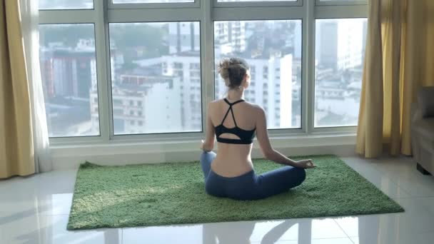 Jonge vrouw beoefenen van meditatie thuis met stadsgezicht achtergrond — Stockvideo