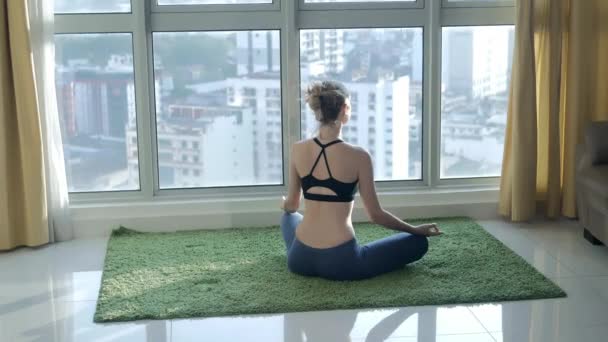 Jeune femme pratiquant la méditation à la maison avec fond de paysage urbain — Video