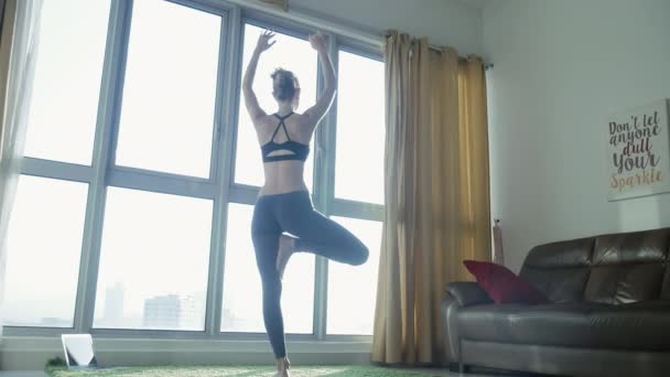 Mujer joven practicando yoga en casa con fondo de paisaje urbano — Vídeo de stock