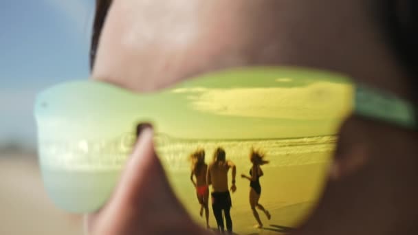 Reflexão em óculos de sol de amigos correndo para o mar . — Vídeo de Stock