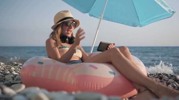 Menina bonita vídeo chats no telefone inteligente na praia — Vídeo de Stock