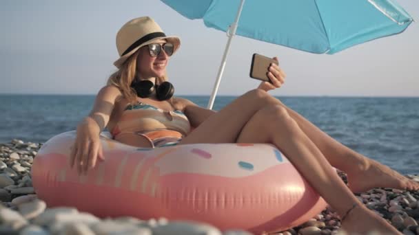 Belle fille chats vidéo sur téléphone intelligent sur la plage — Video