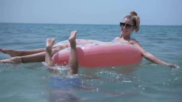 Family relaxing on inflatable toy donut, swimming in blue sea — Stock Video